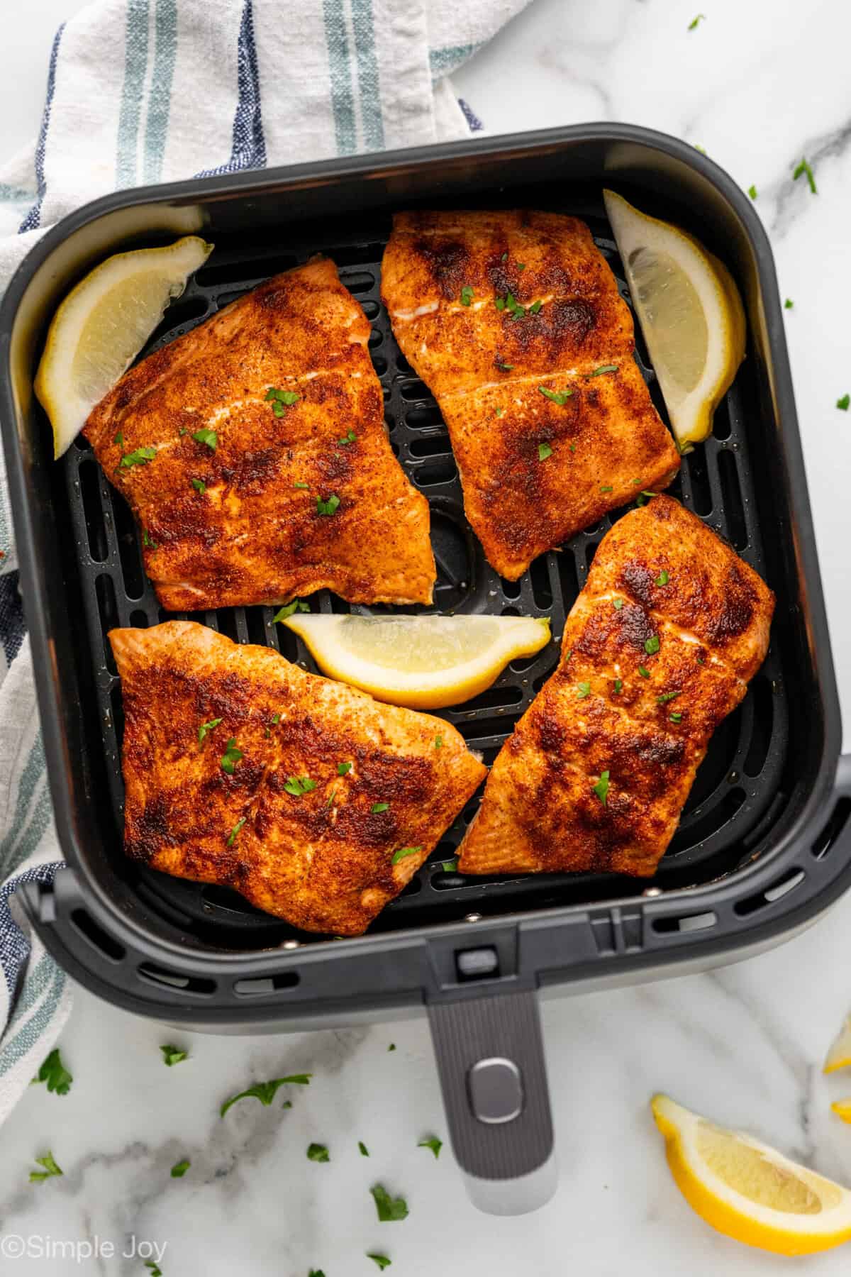 Overhead of air fryer basket of air fryer salmon and lemon slices