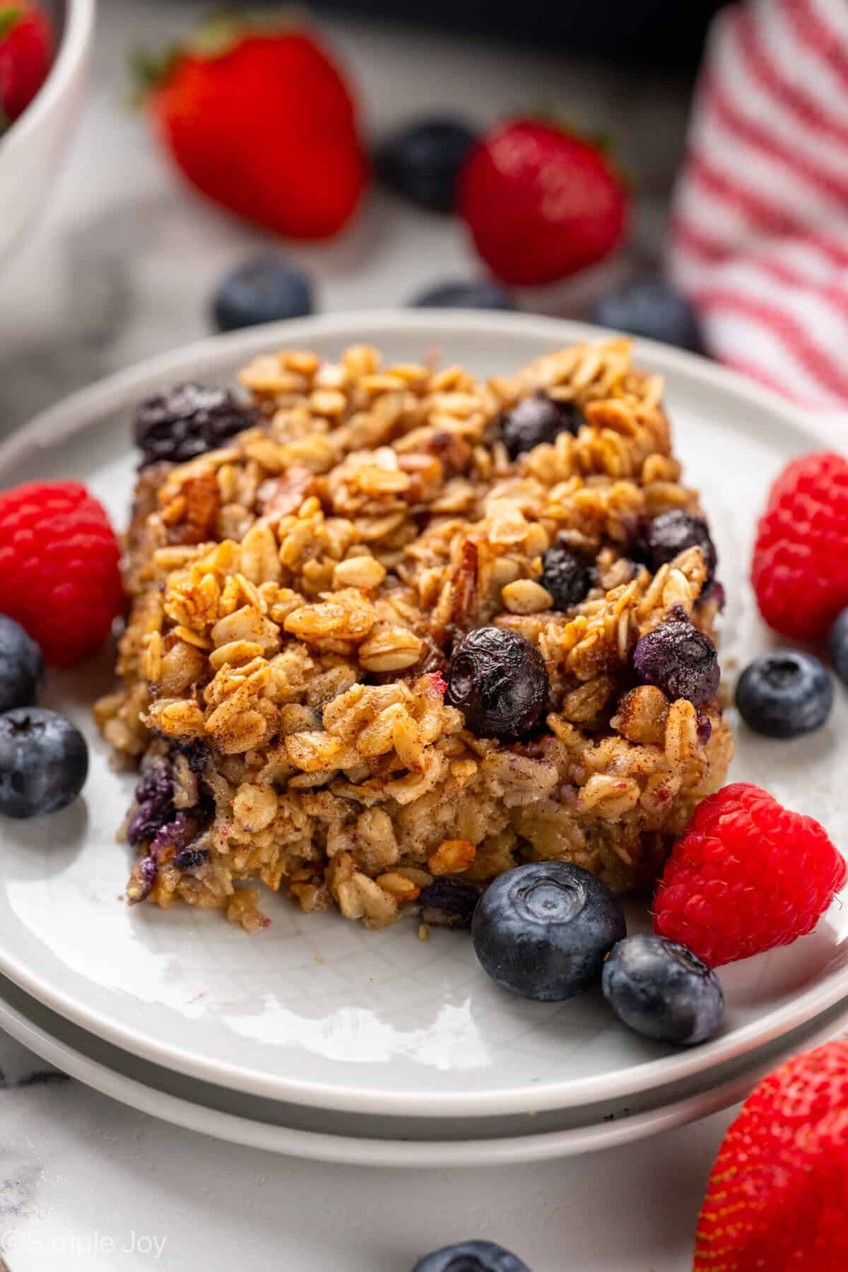 Piece of baked oatmeal on a plate with fresh blueberries and raspberries