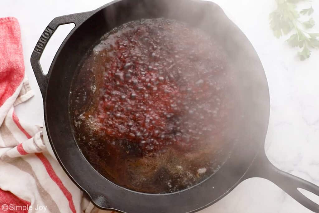 Overhead of cast iron skillet of slow cooker pot roast ingredients