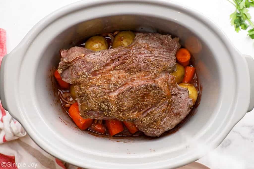 Overhead of slow cooker of pot roast ingredients