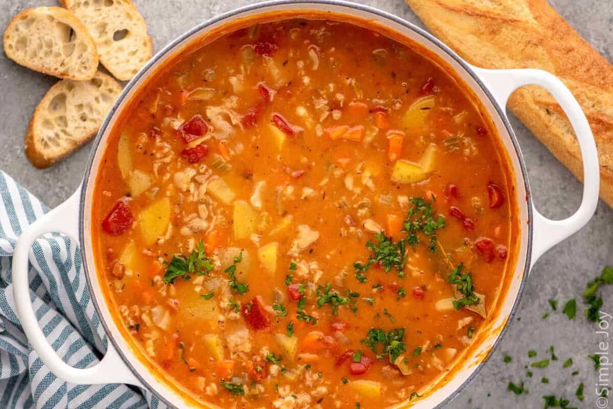 Overhead view of a pot of Manhattan Clam Chowder with bread beside