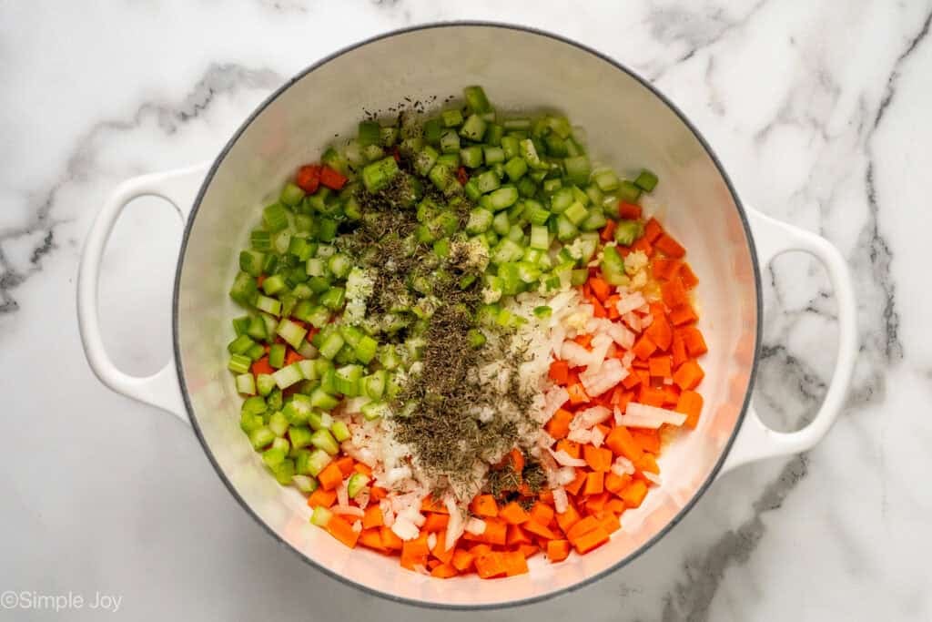 Overhead of chopped, celery, onion, carrot, and spices in a dutch oven