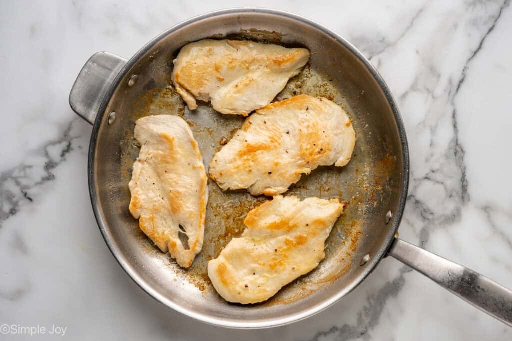 Overhead of skillet of chicken cutlets that have been seared