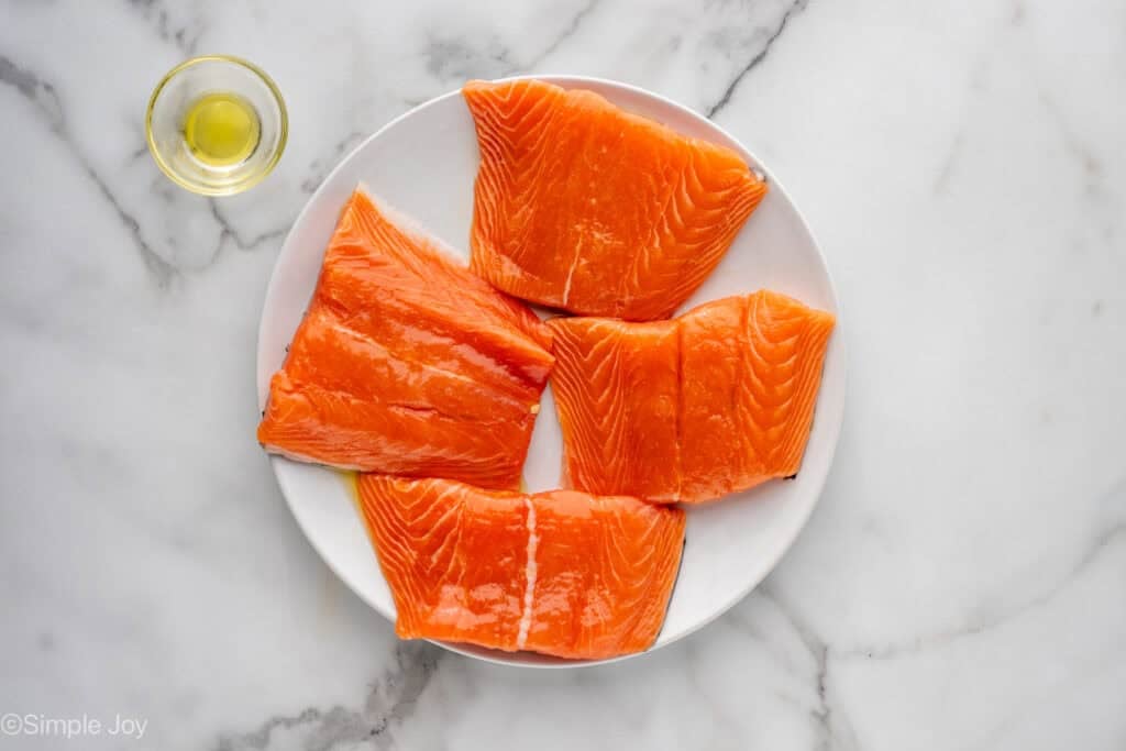 Overhead of plate of salmon with small bowl of olive oil to make air fryer salmon