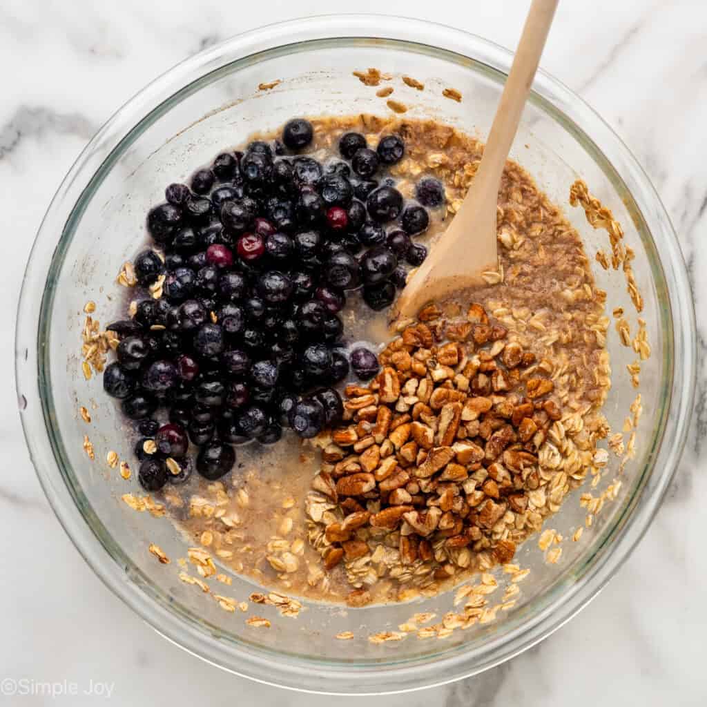 Overhead of glass bowl of baked oatmeal ingredients with wooden spoon