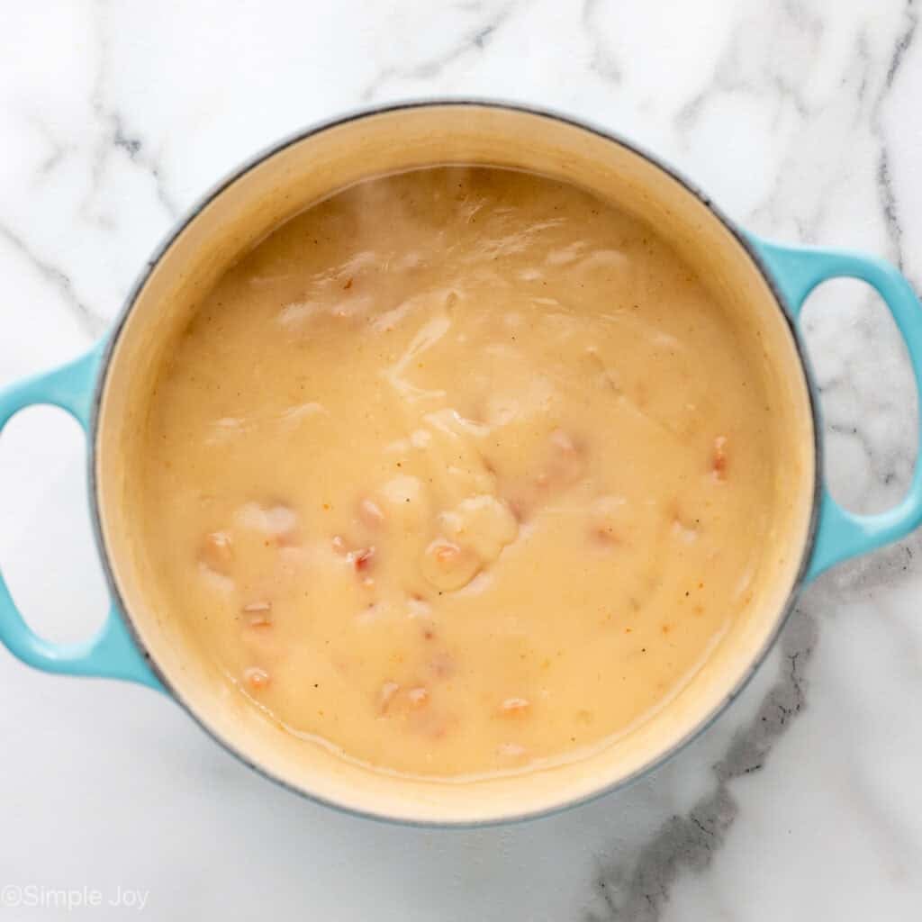 Overhead of pot with a creamy roux and pieces of bacon