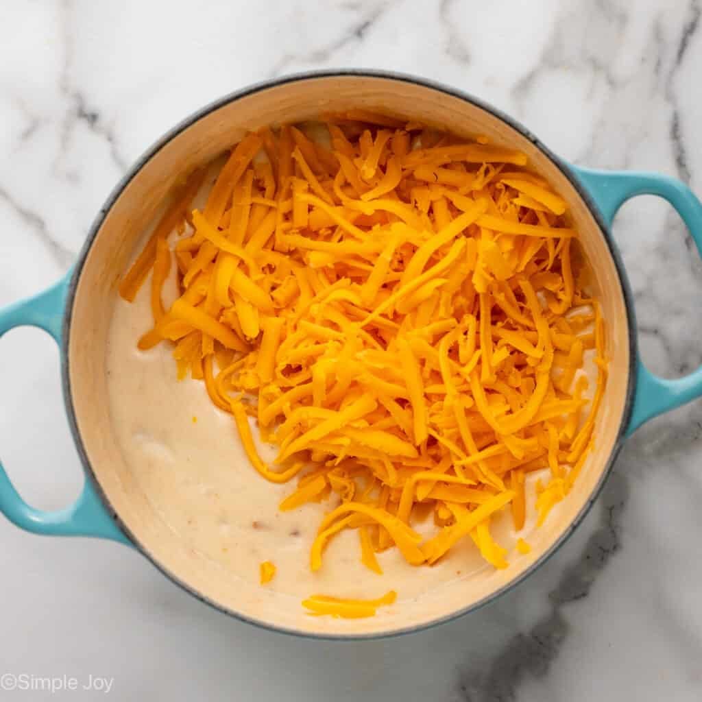 Overhead of pot with a creamy cooked roux and shredded cheese