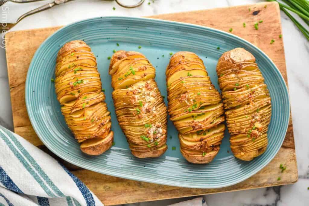 Overhead of hasselback potatoes on a plate garnished and ready for serving.